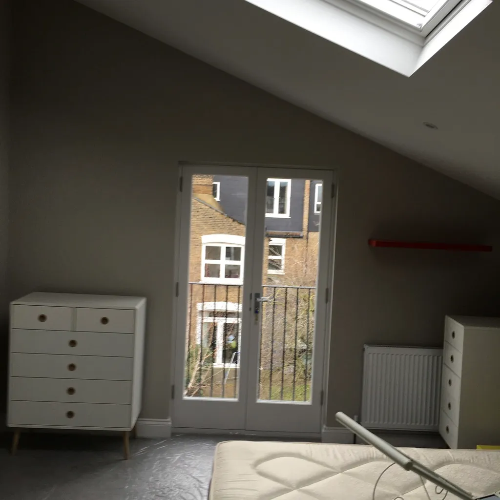 Top-floor bedroom with a Juliet balcony and rooflight in the converted Clapham loft
