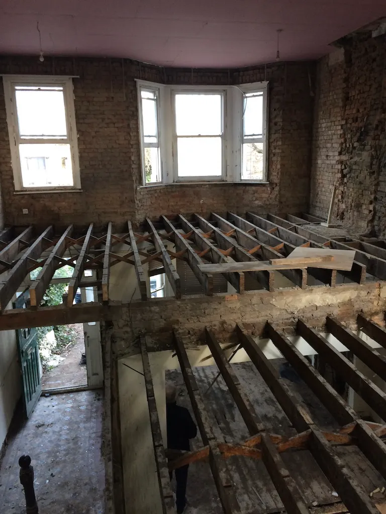 New engineered floor joists installed between flats, with the original brickwork exposed and bay windows beyond