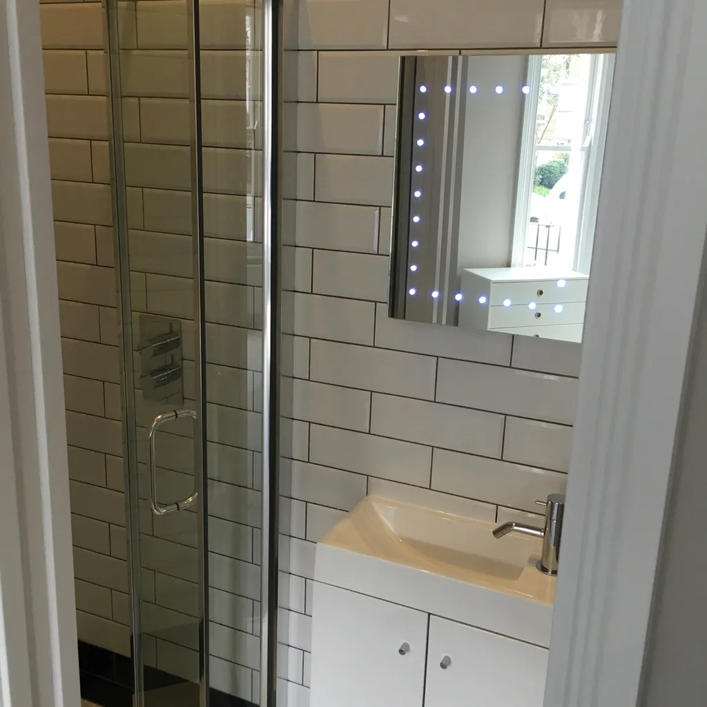 Finished shower room with white metro tiling and an illuminated mirror
