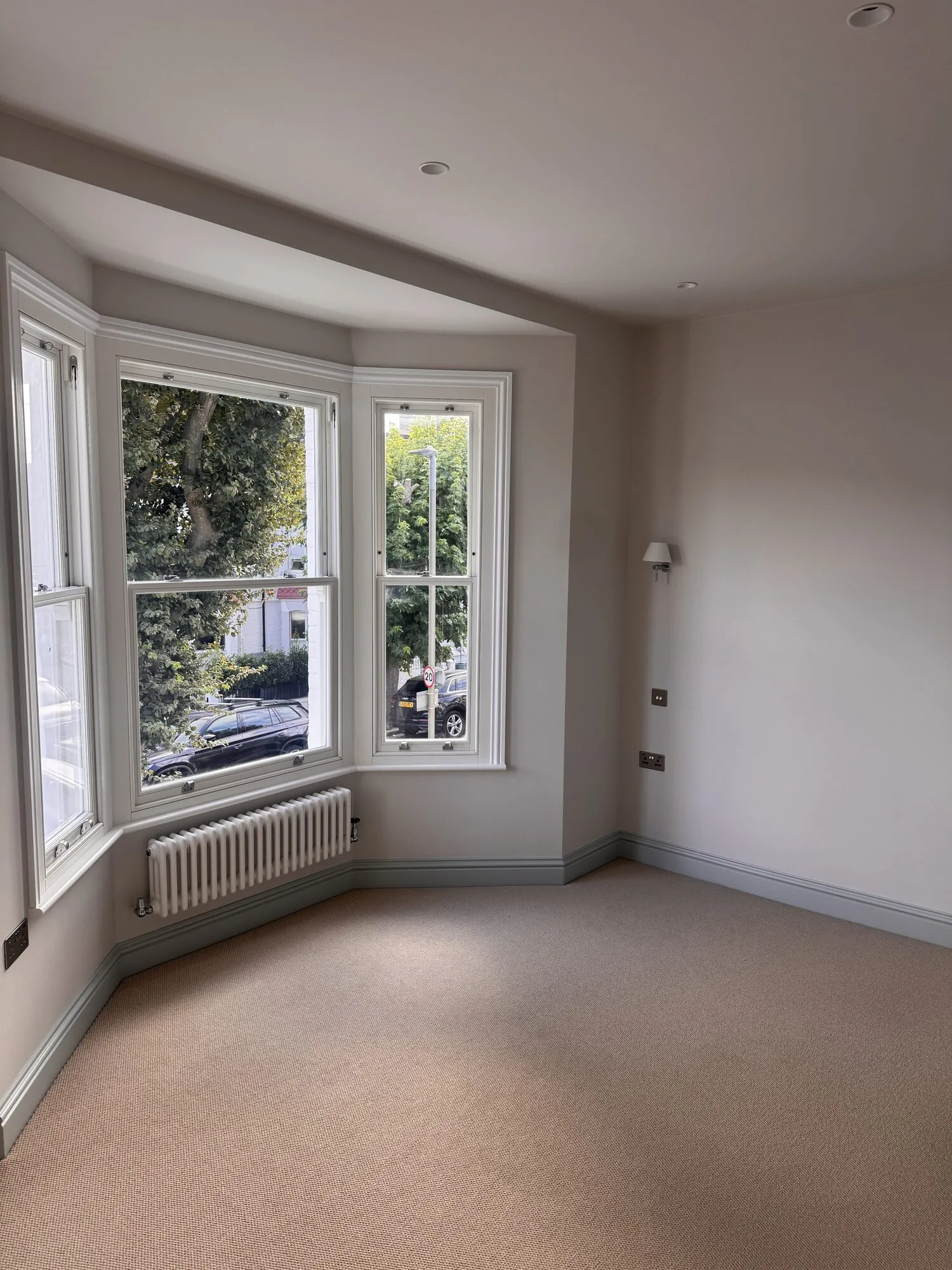 Finished front bedroom with restored bay sash windows, column radiator and new carpet