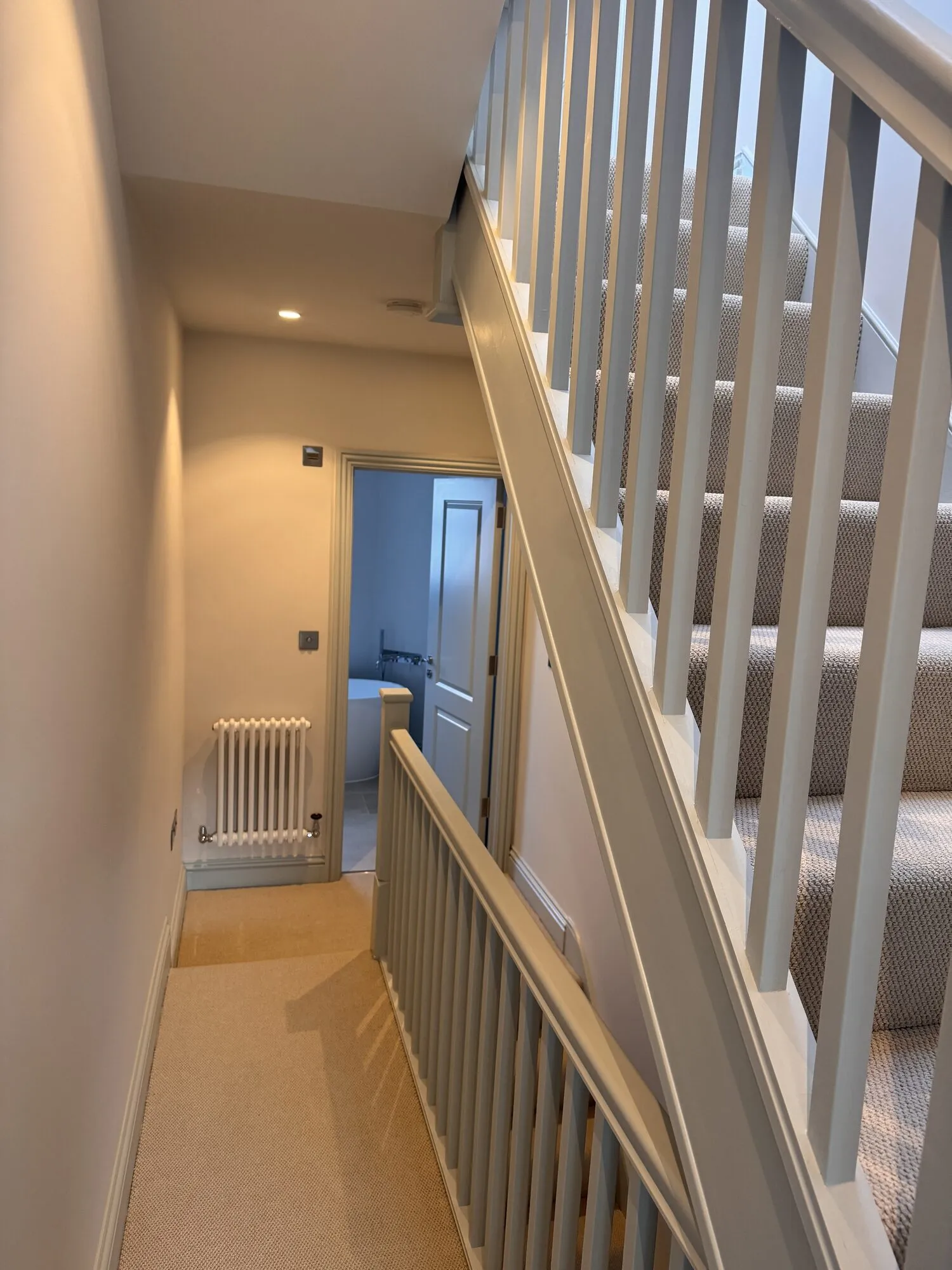 Finished landing and staircase with carpet, looking through to the family bathroom