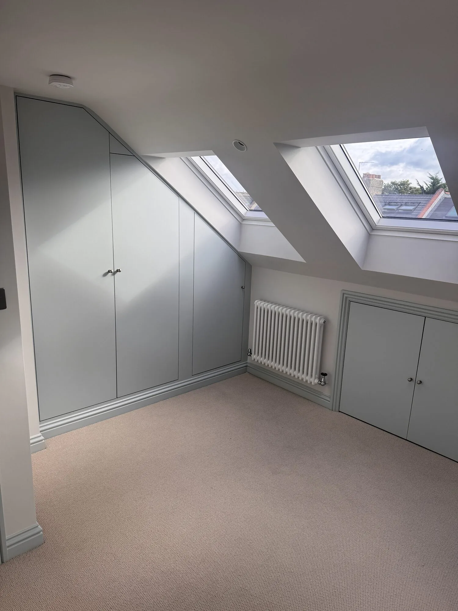 Finished loft bedroom with fitted wardrobes built into the eaves and two rooflights