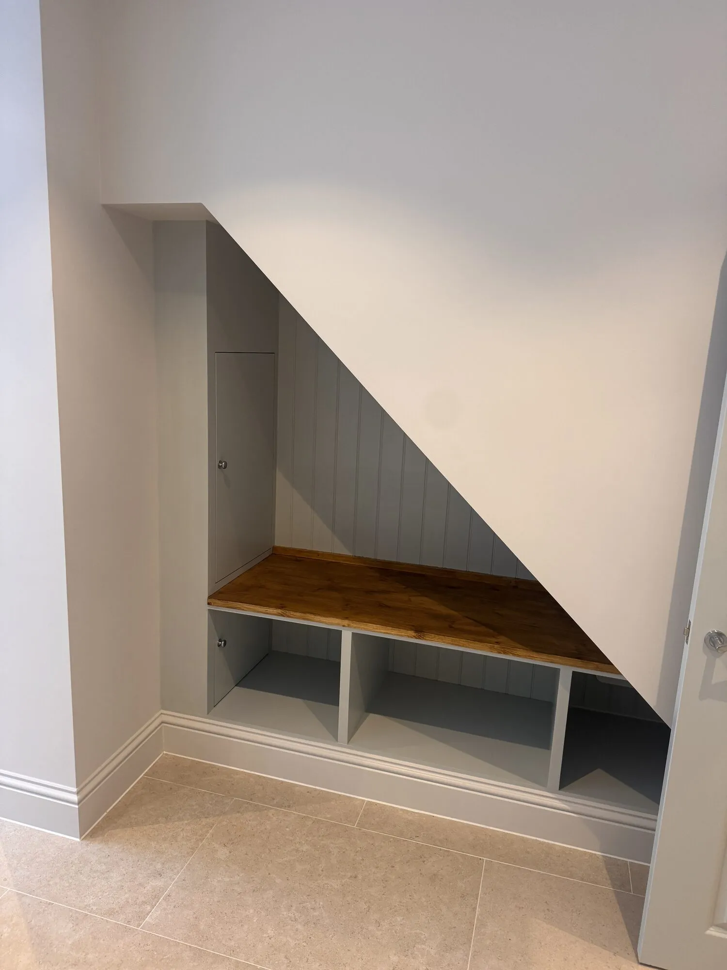 Bespoke joinery built into the space under the stairs, with a timber bench top and open cubbies below