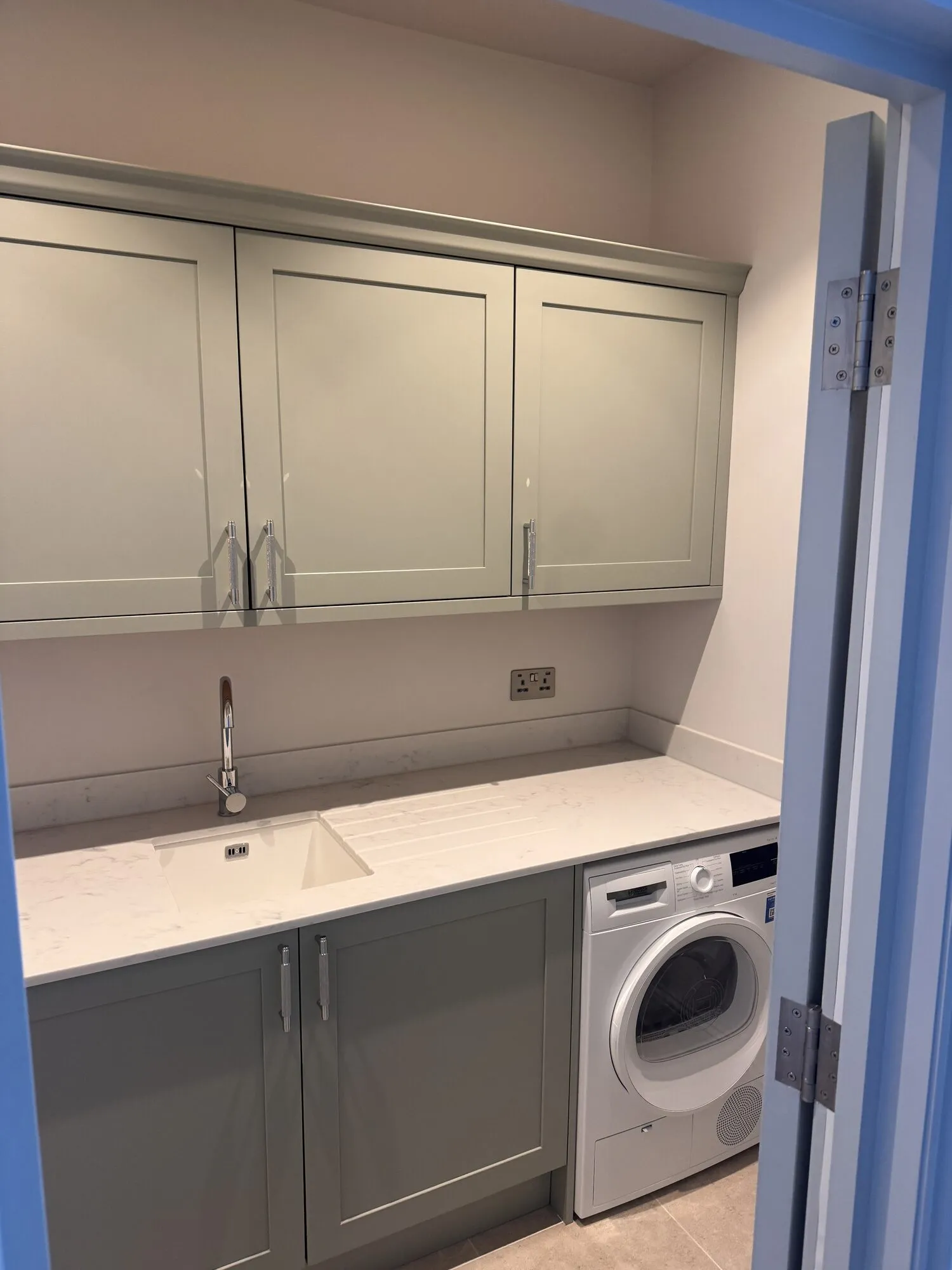 Separate utility room with sage cabinets, quartz worktop, undermounted sink and washing machine