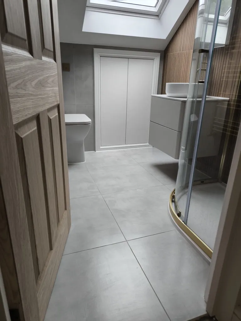 Finished loft bathroom with rooflight, large-format grey tiling and timber slatted panelling